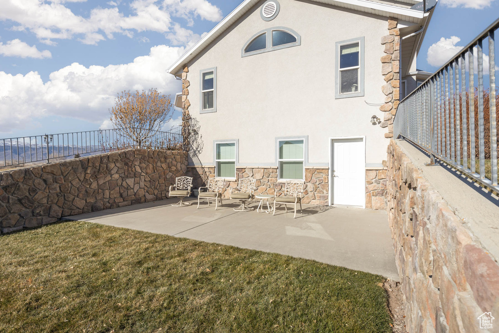 Rear view of property with a patio area, stone siding, and stucco siding