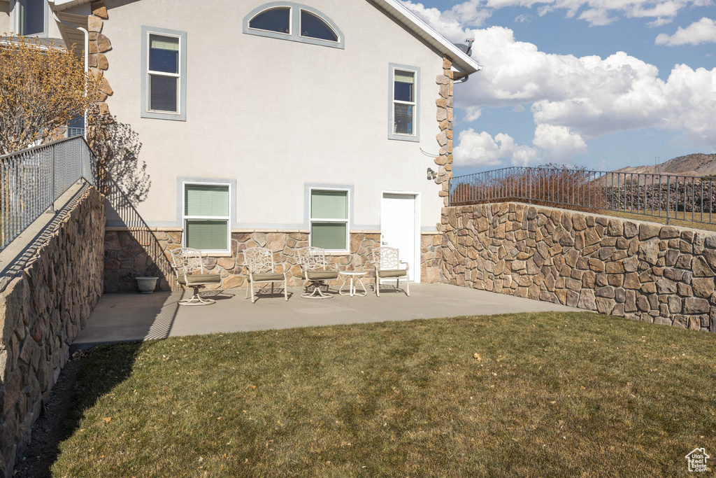 Back of property with a patio area, fence, a lawn, and stucco siding