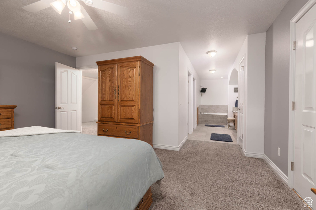 Bedroom featuring light carpet, ensuite bath, baseboards, and ceiling fan