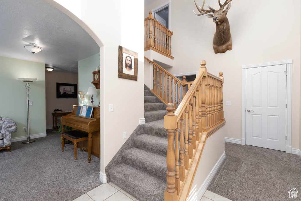 Stairs with baseboards, arched walkways, carpet flooring, and tile patterned floors