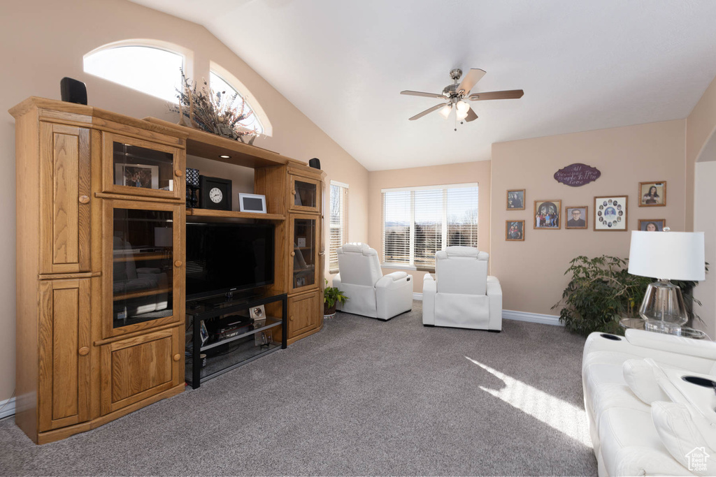 Carpeted living area with lofted ceiling, baseboards, and a ceiling fan