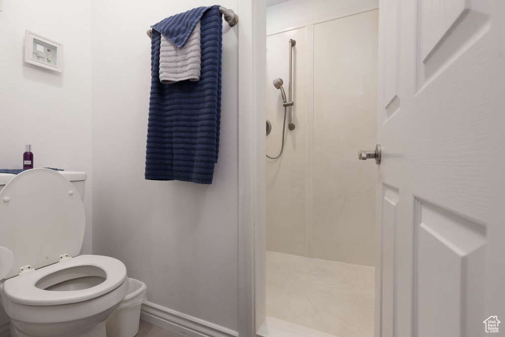 Full bathroom with toilet, a stall shower, and baseboards