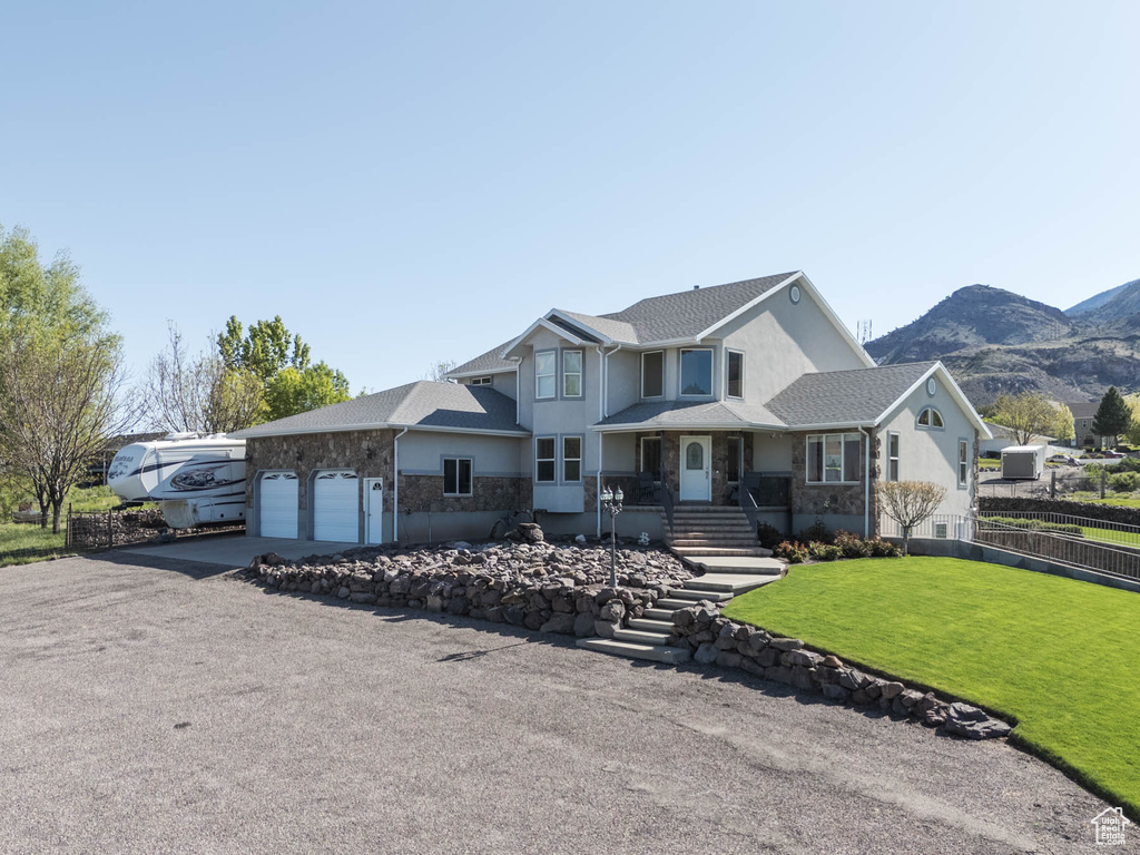 View of front of house featuring stucco siding, an attached garage, a mountain view, driveway, and stone siding