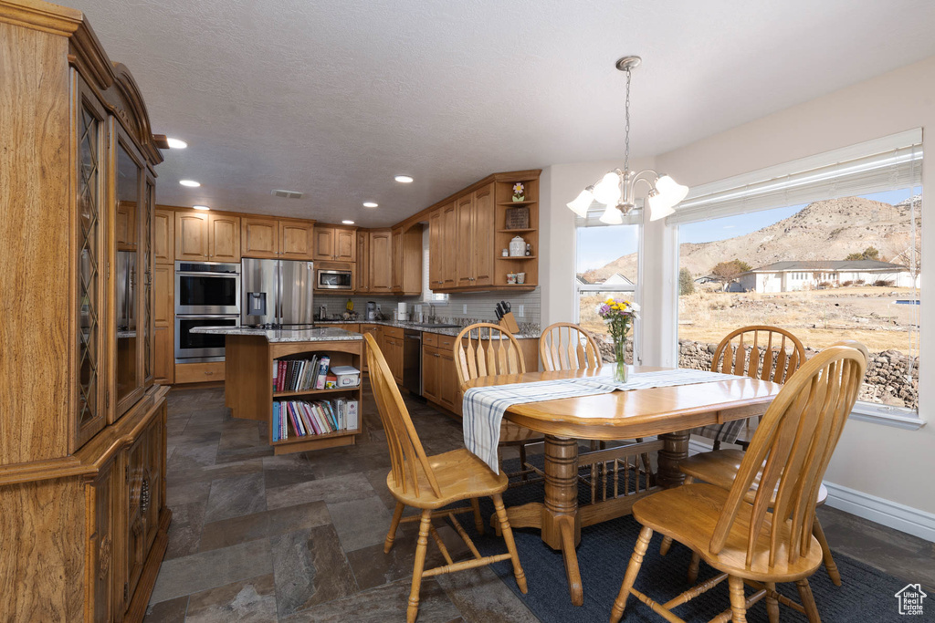 Dining room featuring a mountain view, recessed lighting, a notable chandelier, baseboards, and stone finish flooring