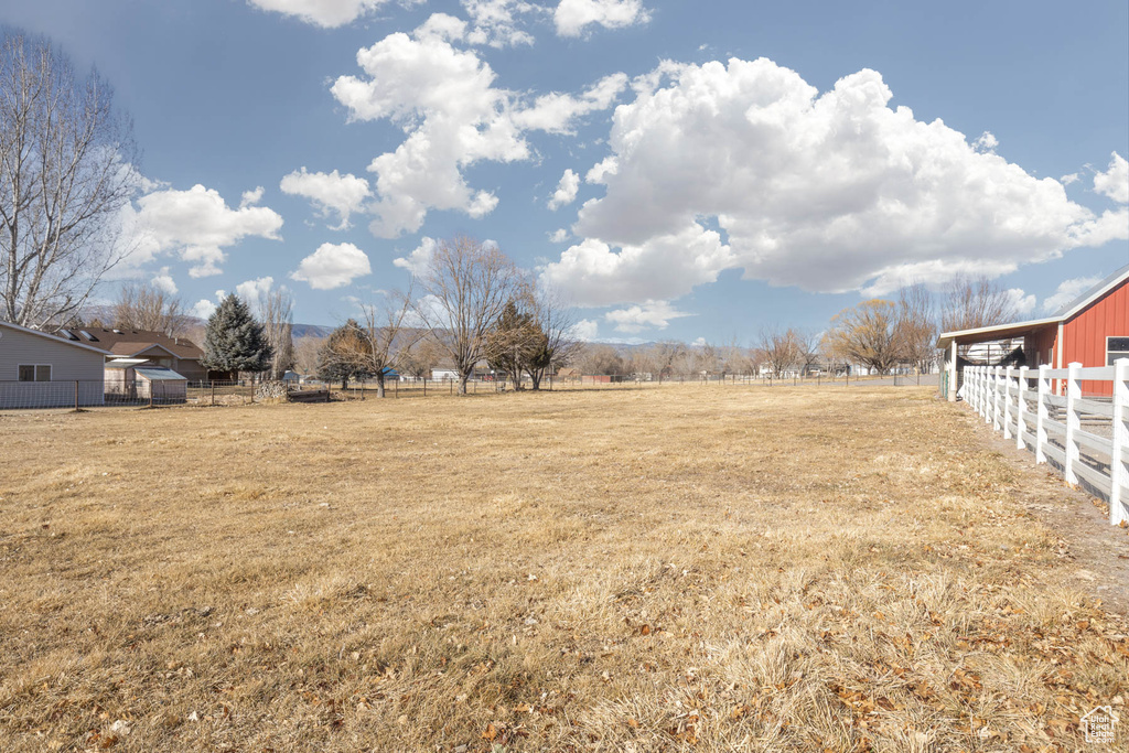 View of yard with an outbuilding, a rural view, and fence