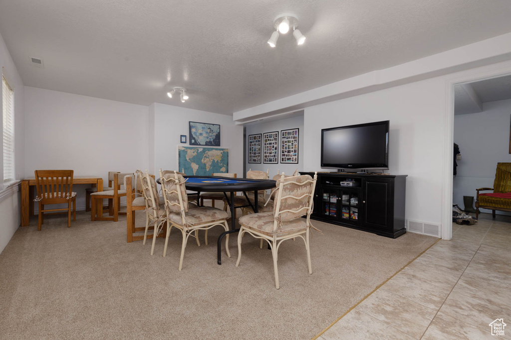 Carpeted dining space featuring visible vents, a textured ceiling, and tile patterned floors