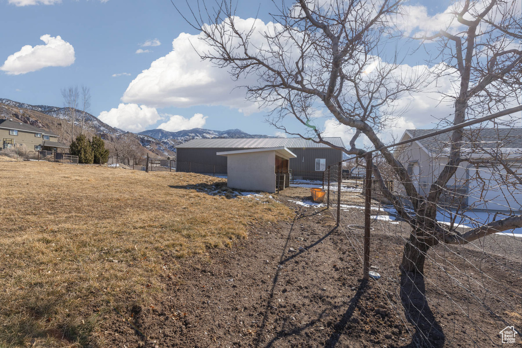 View of yard featuring a mountain view, an outdoor structure, and fence