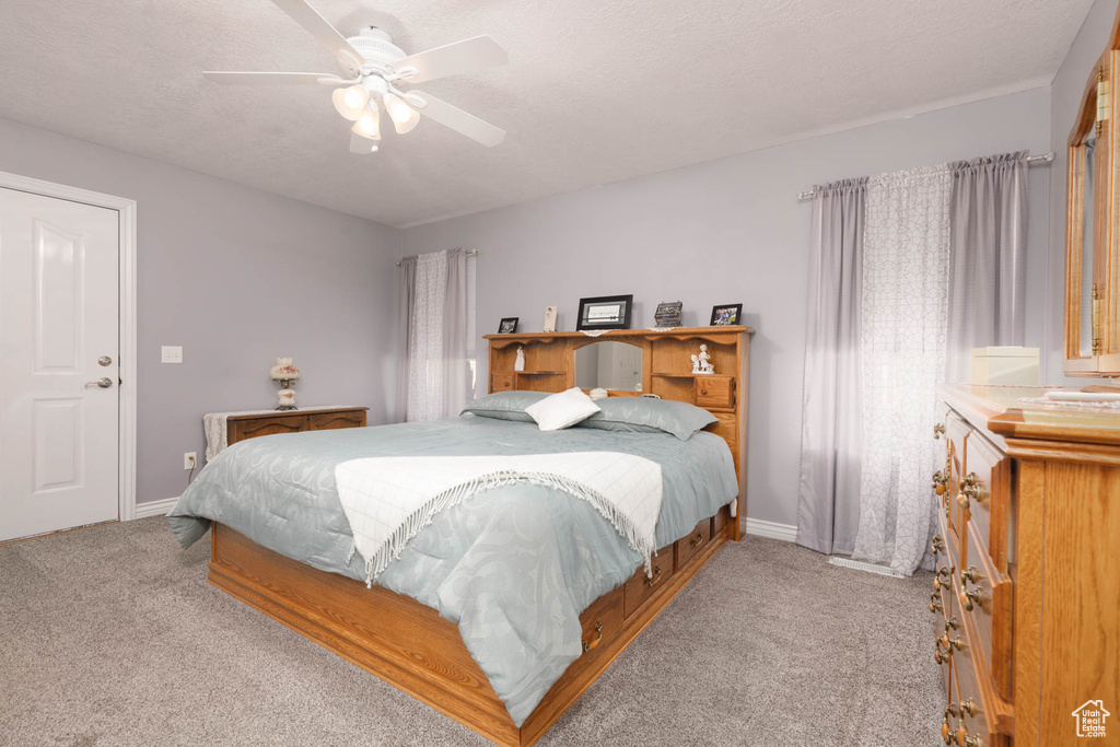 Carpeted bedroom with ceiling fan, a textured ceiling, and baseboards