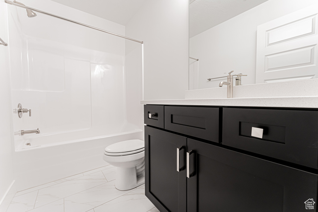Bathroom featuring vanity, washtub / shower combination, and marble look tiles