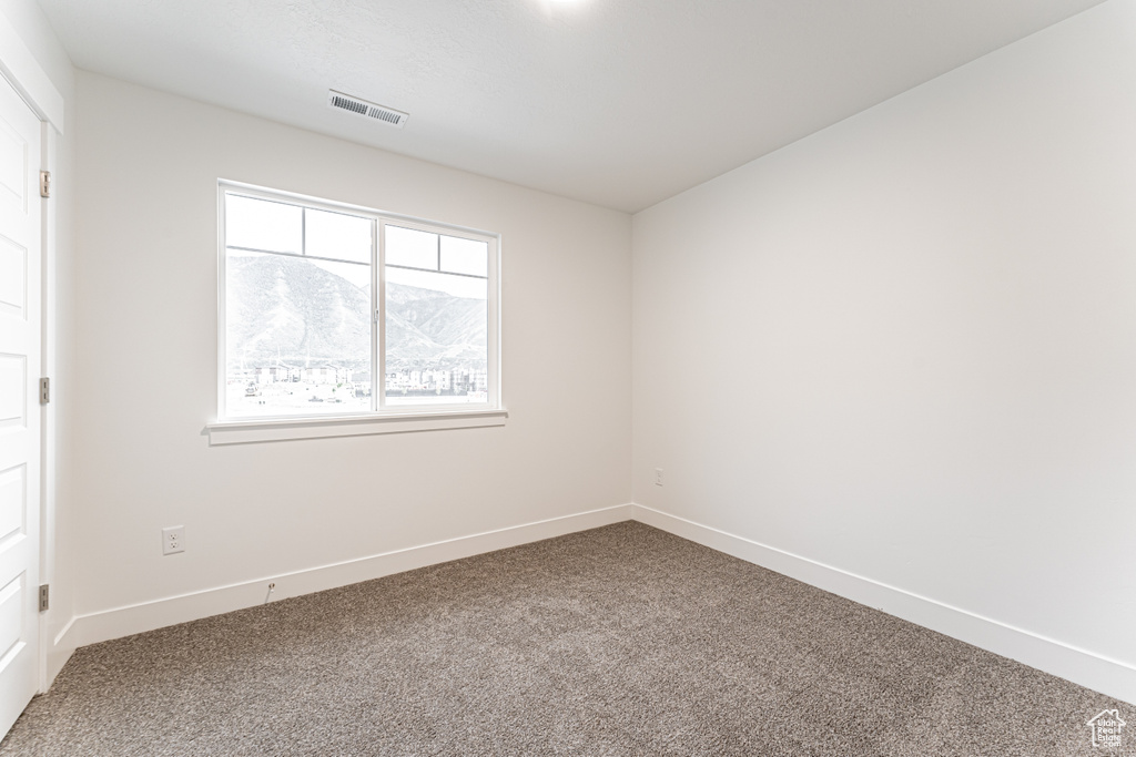 Unfurnished bedroom with carpet and a mountain view