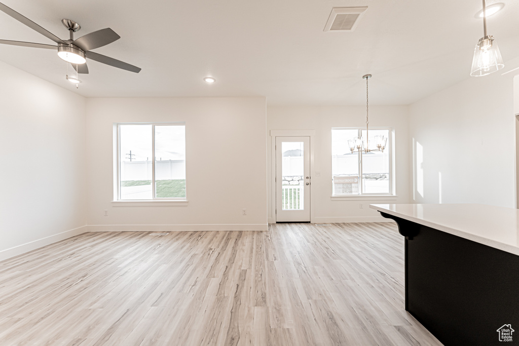 Unfurnished living room with light wood-style floors, a chandelier, a ceiling fan, and recessed lighting