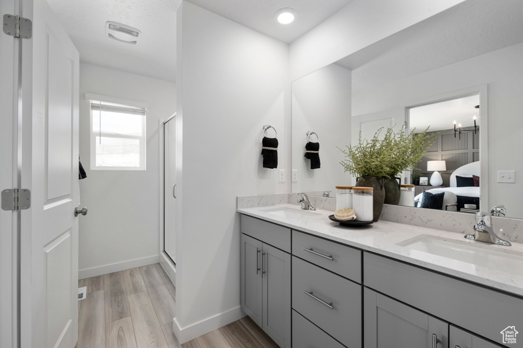 Bathroom featuring double vanity, wood finished floors, a sink, and a shower stall