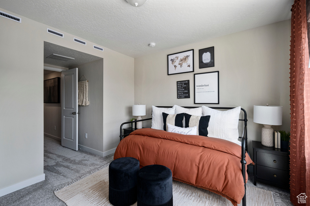 Bedroom with a textured ceiling, carpet floors, visible vents, and baseboards