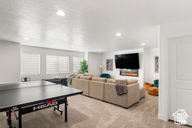 Playroom featuring light carpet, a textured ceiling, a glass covered fireplace, and recessed lighting