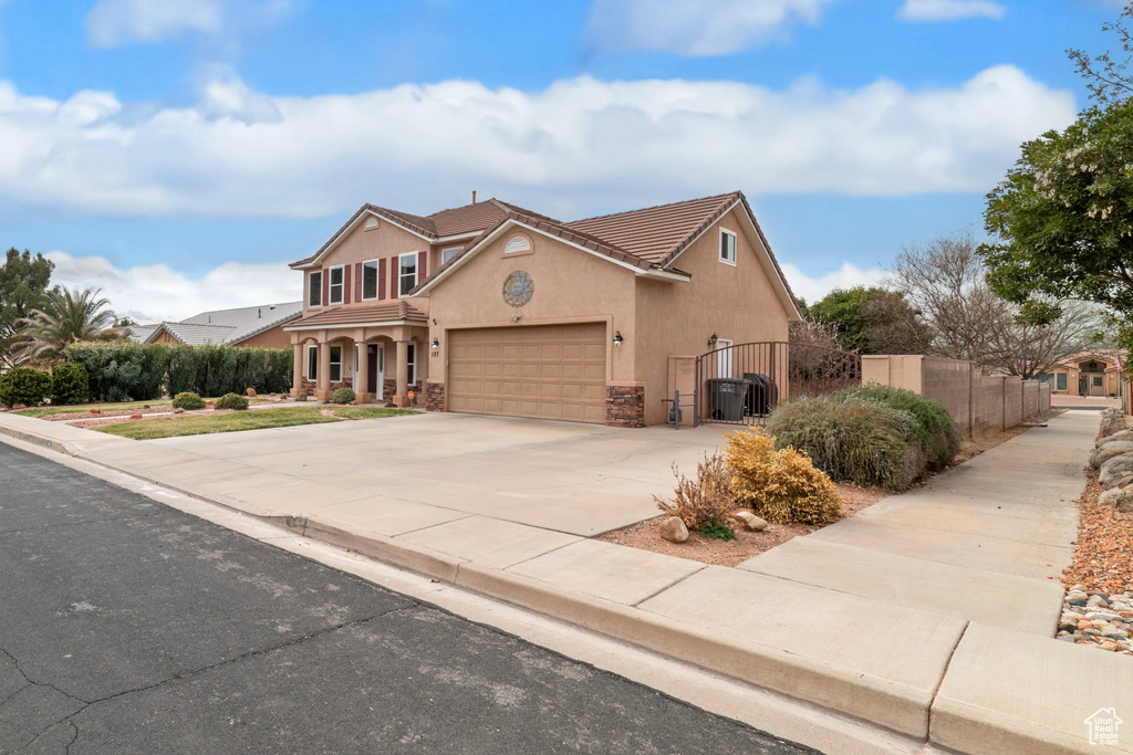 Traditional-style house featuring a tiled roof, a gate, stucco siding, a garage, and concrete driveway
