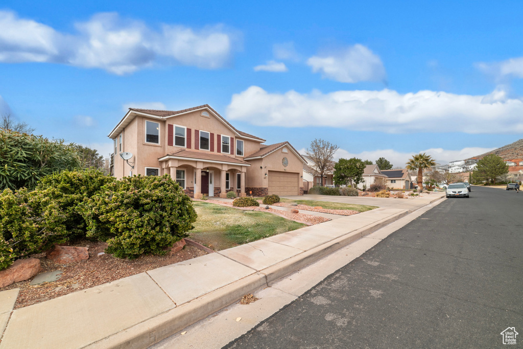 Traditional-style home with stucco siding, an attached garage, concrete driveway, and a porch