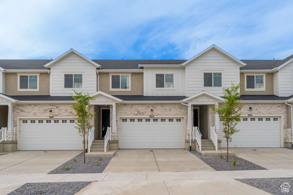Townhome / multi-family property featuring an attached garage, board and batten siding, and concrete driveway