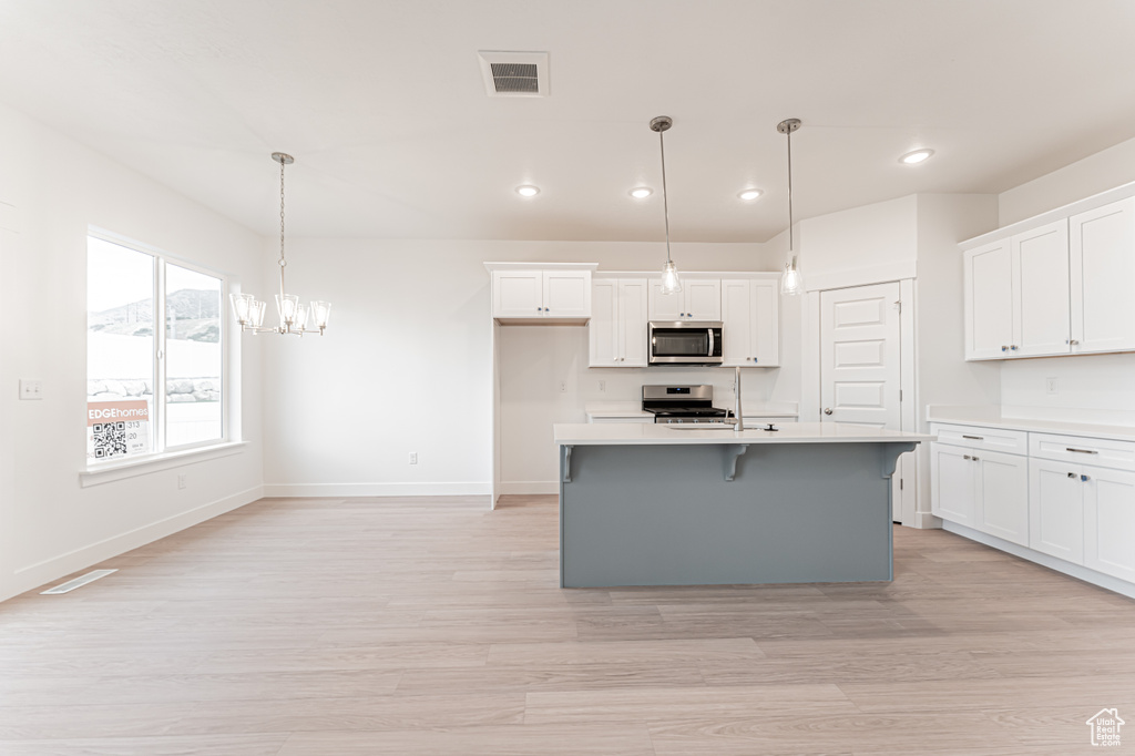 Kitchen with stainless steel microwave, range, recessed lighting, white cabinetry, and light countertops