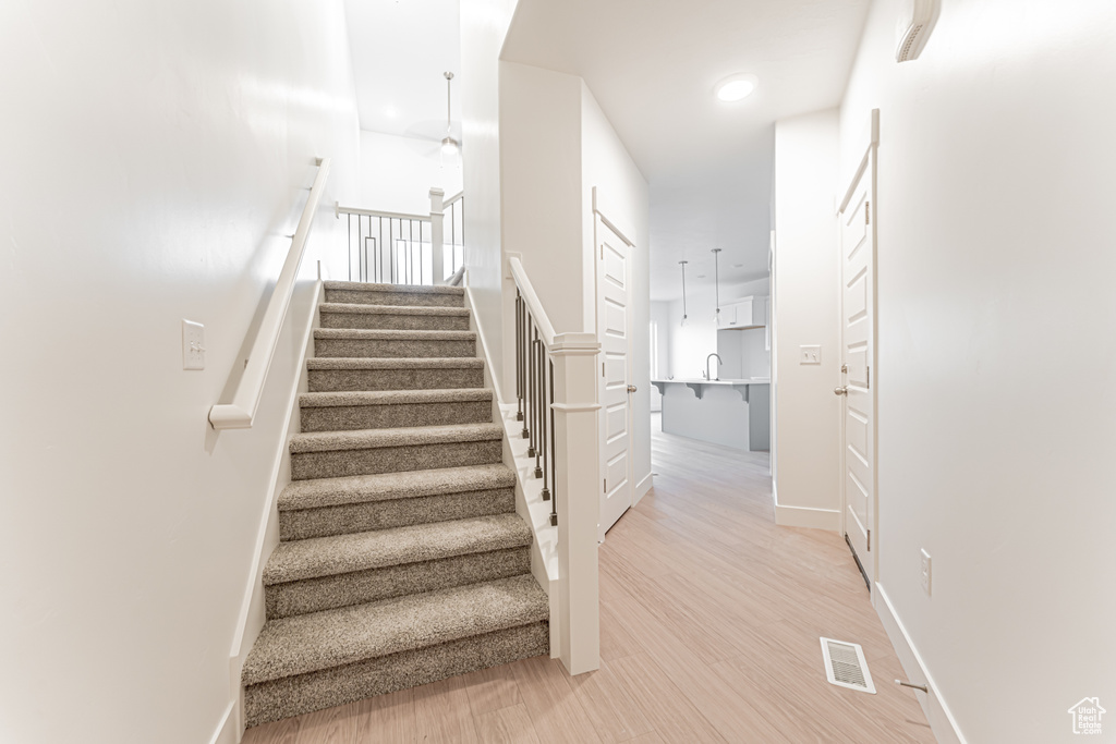 Stairs featuring wood finished floors and recessed lighting