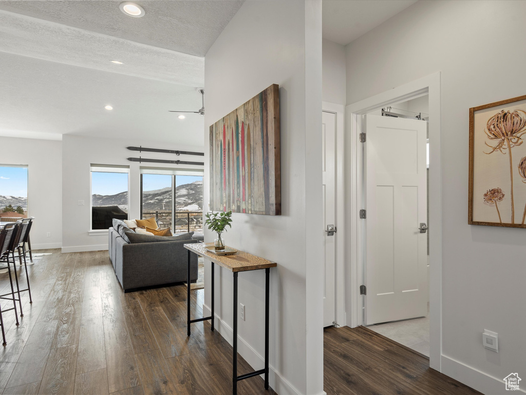 Hall with recessed lighting, a textured ceiling, baseboards, and wood finished floors