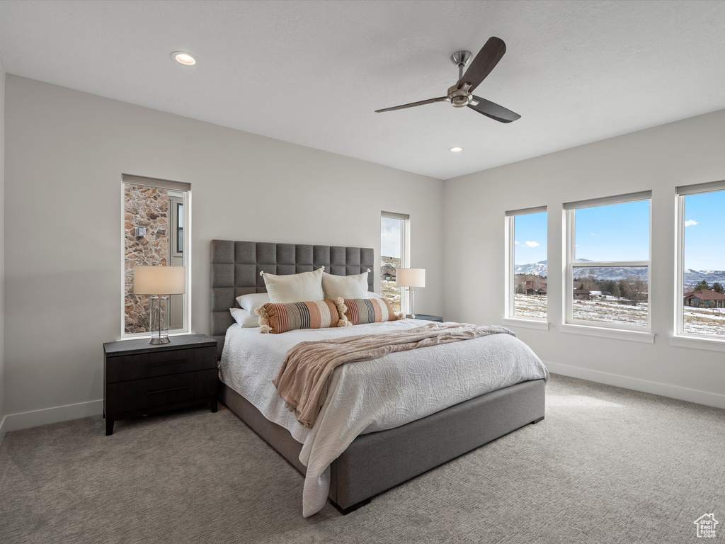 Bedroom featuring light carpet, a ceiling fan, and baseboards