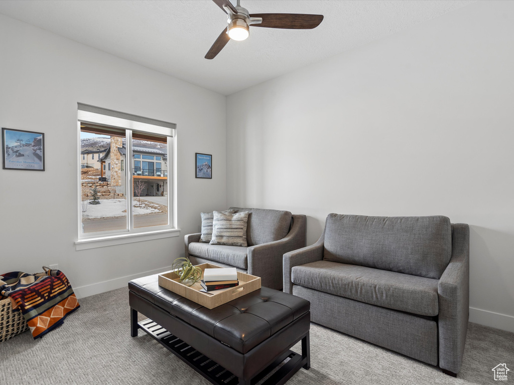 Carpeted living area featuring baseboards and a ceiling fan