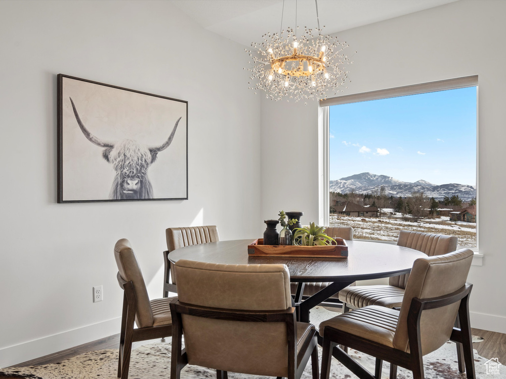 Dining area with an inviting chandelier, baseboards, a mountain view, and wood finished floors