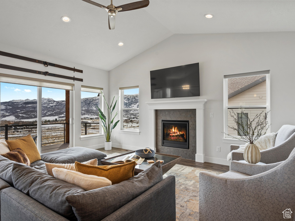 Living room featuring recessed lighting, vaulted ceiling, wood finished floors, a tile fireplace, and baseboards