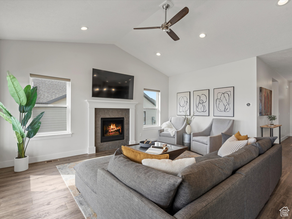 Living room featuring lofted ceiling, recessed lighting, a tile fireplace, and wood finished floors