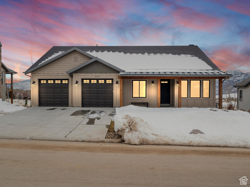 View of front of home featuring board and batten siding, concrete driveway, an attached garage, and a standing seam roof