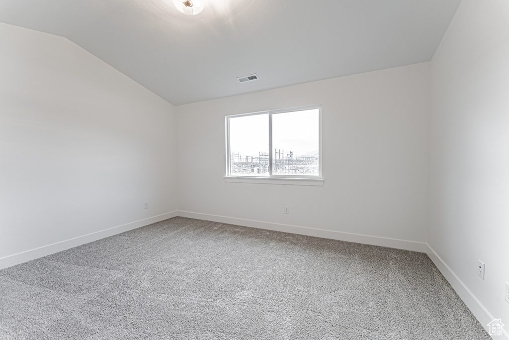 Unfurnished room with vaulted ceiling and carpet floors