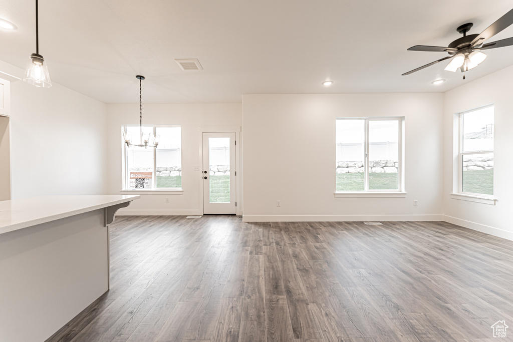Unfurnished living room featuring dark wood finished floors, a chandelier, ceiling fan, and recessed lighting