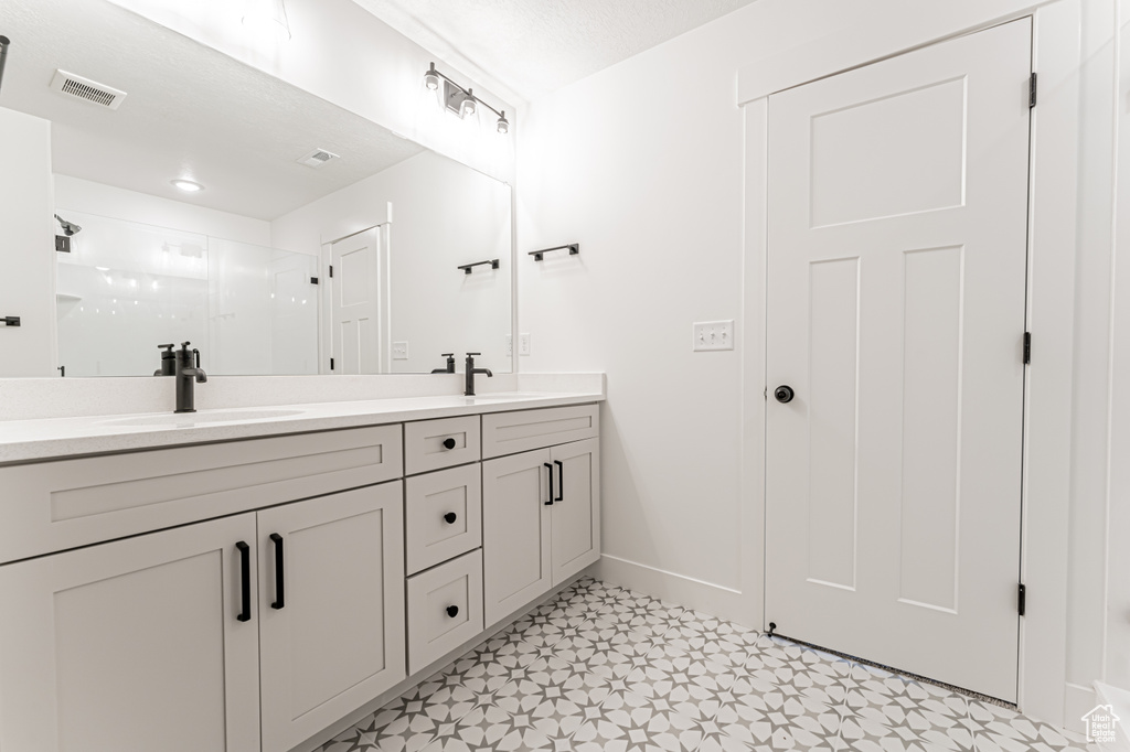 Bathroom featuring double vanity, a shower stall, and tile patterned floors