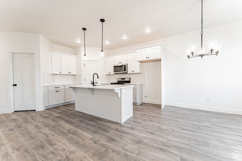 Kitchen featuring appliances with stainless steel finishes, backsplash, light countertops, light wood-type flooring, and recessed lighting