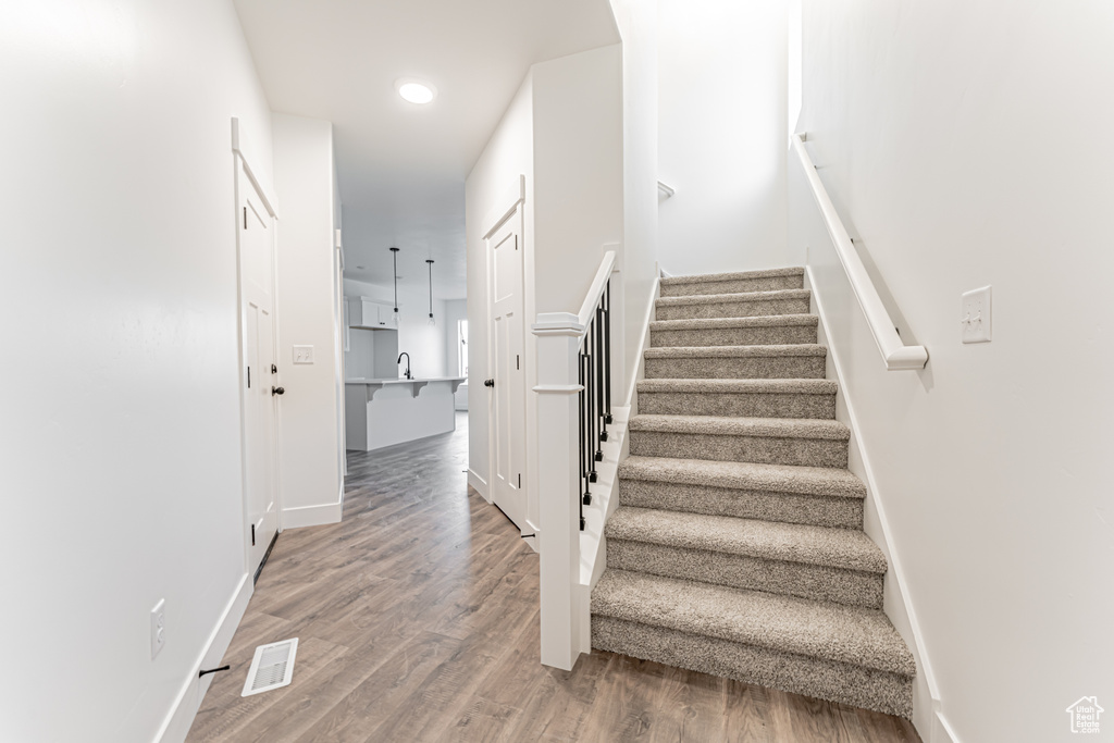 Staircase with wood finished floors and recessed lighting