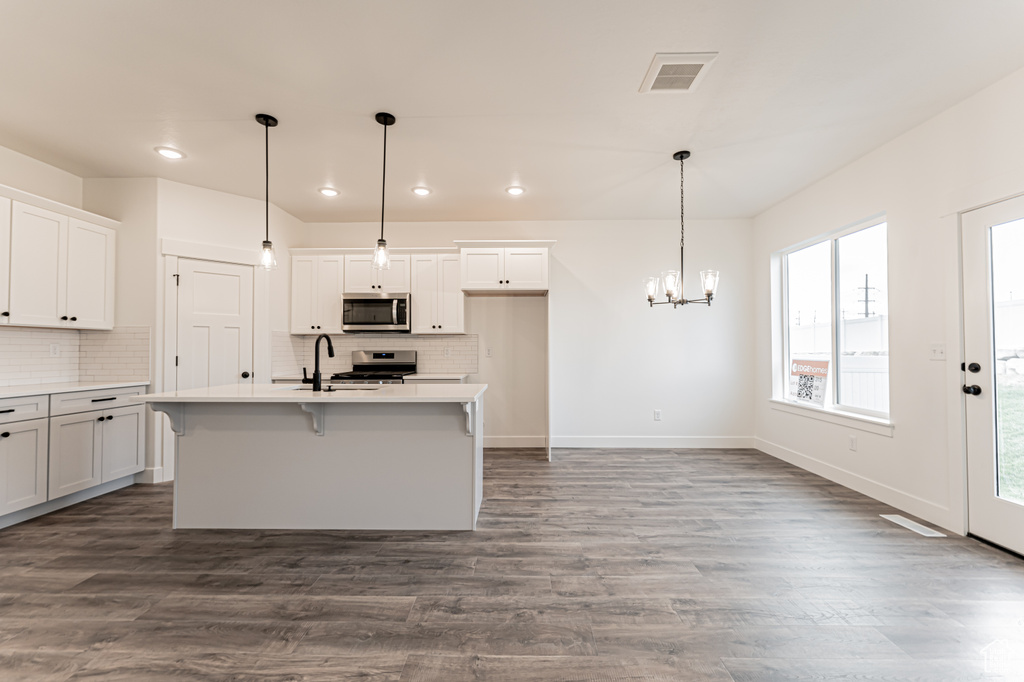 Kitchen featuring appliances with stainless steel finishes, a chandelier, recessed lighting, backsplash, and dark wood finished floors