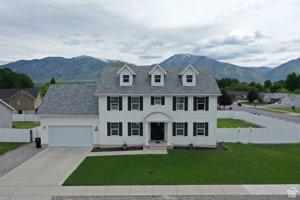 Colonial inspired home featuring a garage, concrete driveway, a mountain view, and a shingled roof