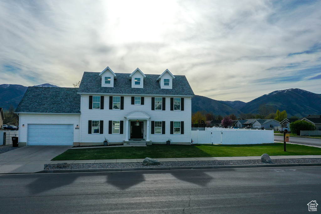 Colonial home featuring fence, an attached garage, a front yard, a mountain view, and driveway
