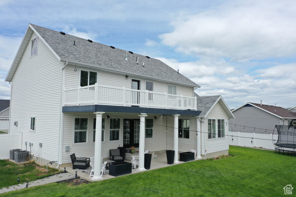 Back of house featuring a trampoline, outdoor lounge area, a patio, and roof with shingles