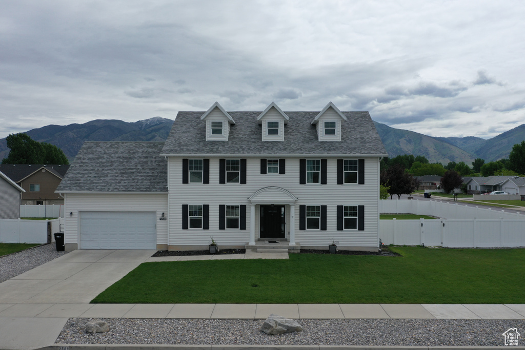 Colonial inspired home featuring an attached garage, driveway, a mountain view, and roof with shingles