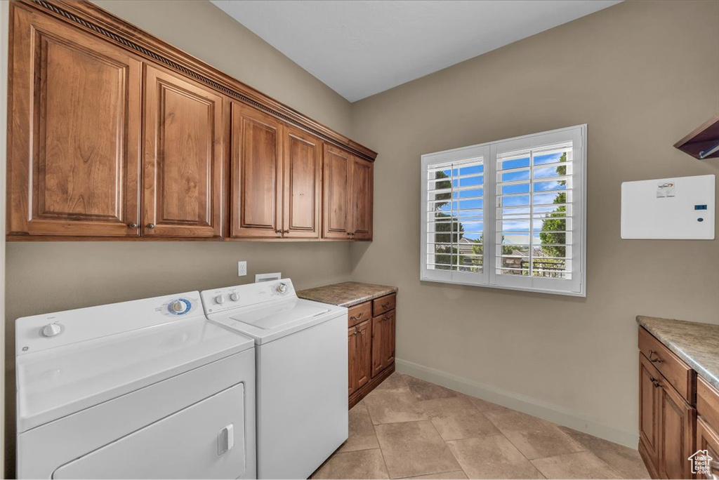 Laundry room featuring cabinet space, washing machine and dryer, and light tile patterned floors