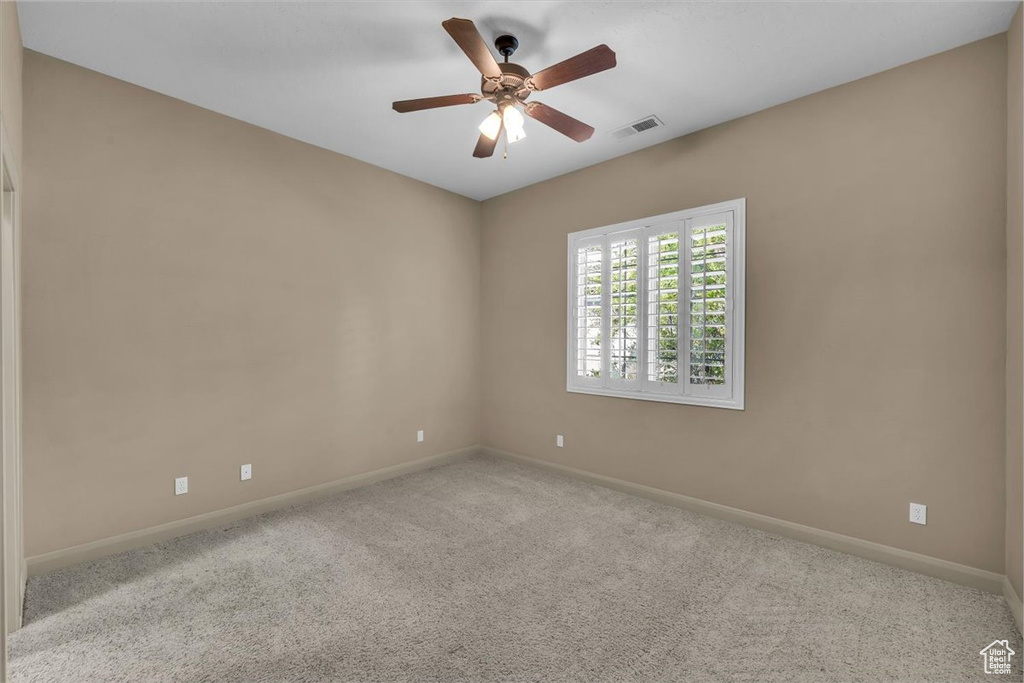 Carpeted empty room featuring baseboards and ceiling fan