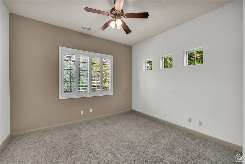 Carpeted empty room featuring baseboards and ceiling fan
