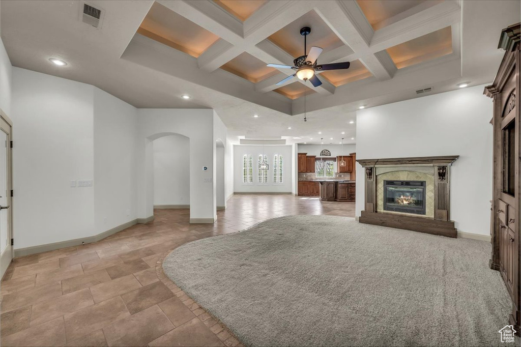 Living room featuring coffered ceiling, ceiling fan, arched walkways, beamed ceiling, and recessed lighting