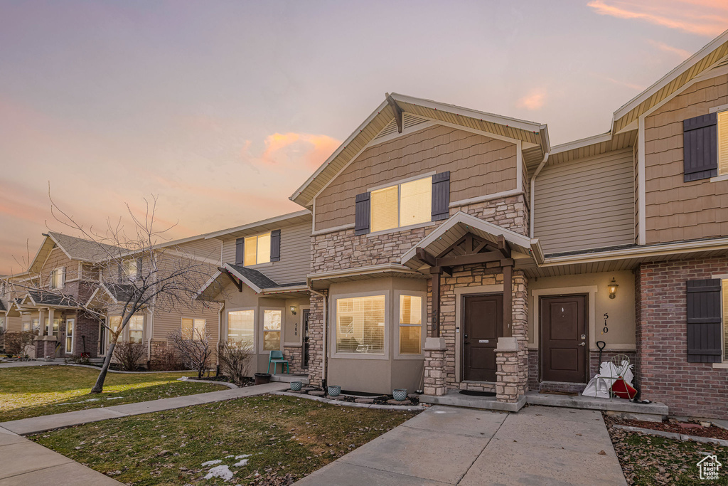 View of front of home with stone siding and a lawn