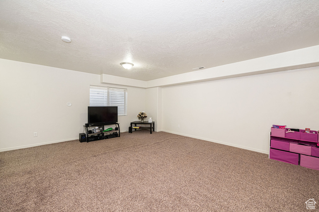 Basement featuring carpet floors, visible vents, a textured ceiling, and baseboards