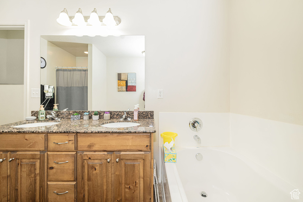 Full bathroom with double vanity, a garden tub, and a sink