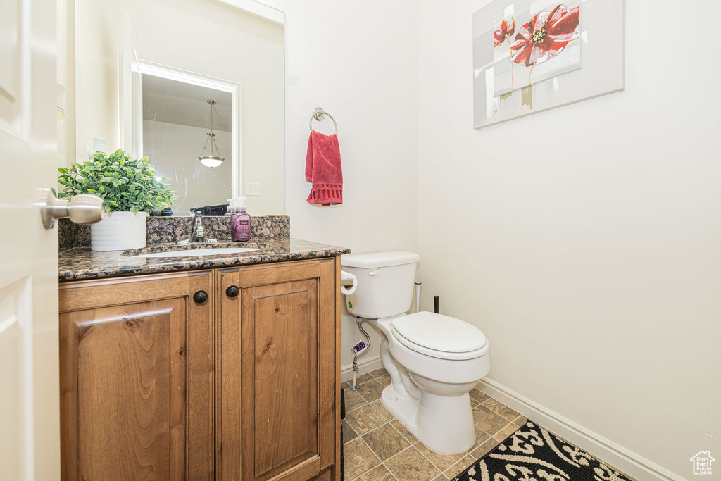 Bathroom featuring toilet, baseboards, and vanity