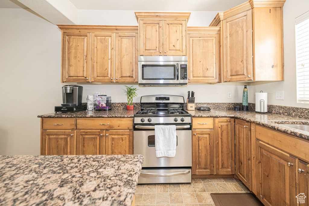 Kitchen with appliances with stainless steel finishes and dark stone counters