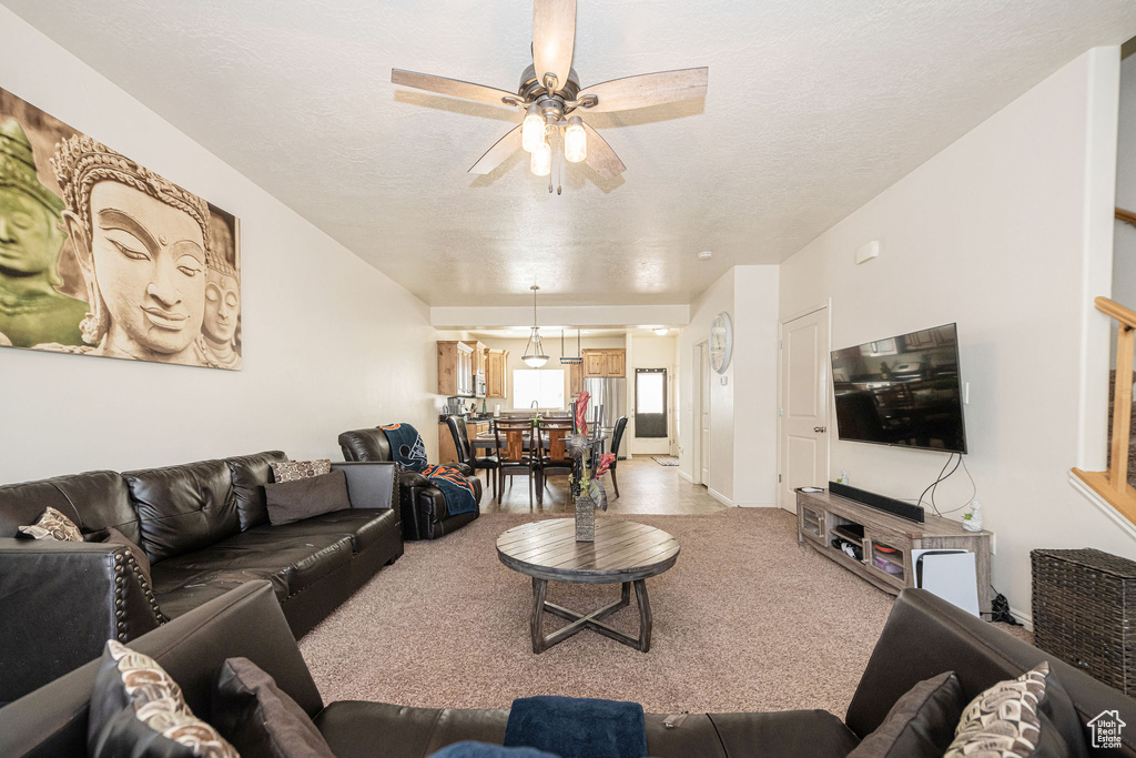 Living room with light carpet, ceiling fan, and a textured ceiling